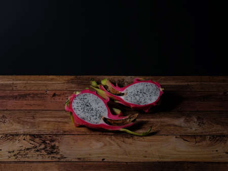 Dragon Fruit split in to two pieces on the wooden table in dark backgroundの写真素材