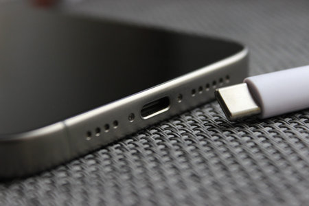 Braided USB-C cable beside a smartphone with USB-C port on woven surface, charging concept.