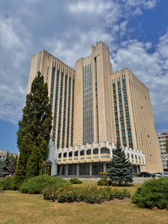 Tall administrative complex in Chisinau with vertical lines and teal window bands set against a dynamic sky and landscaped grounds.の写真素材
