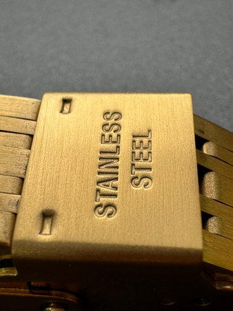 Extreme close-up of a wrist watch bracelet clasp with embossed text STAINLESS STEEL, brushed...