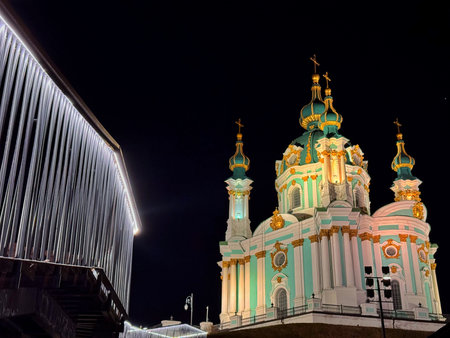 Night view of St Andrew Church in Kyiv, Ukraine. Baroque architecture with teal and white facade, gold domes and crosses, bright exterior lighting.の写真素材