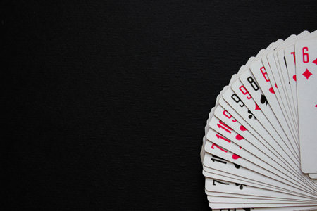 A deck of playing cards fanned in an arc on a black background, leaving ample copy space for text....