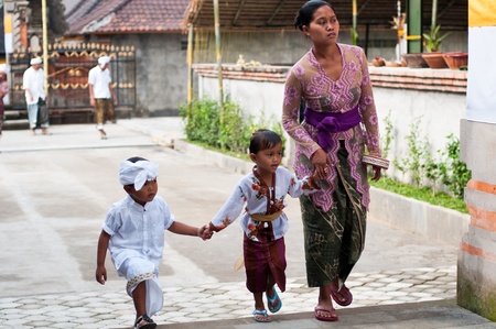 Tirta Empul, Bali, Indonesia - October 11, 2011  woman with here children walking to Tirta Empul Temple to give offerings to the spiritsのeditorial素材