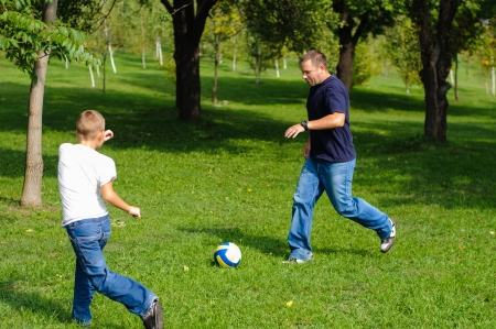 Young boy playing football with his father outdoorsの写真素材