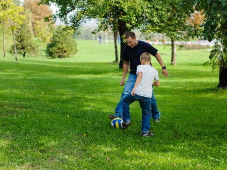 Young boy playing football with his father outdoorsの写真素材