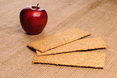 Red apple with crispbread on sacking backgroundの写真素材