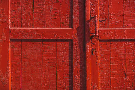 An old wood door with cracked red paint and grungeの写真素材