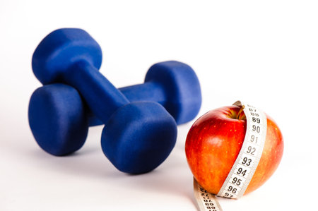 Blue dumbbells and red apple with measure tape isolated on a white backgroundの写真素材