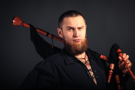 Young man with beard in scottish costume with pipe in his hand. Studio shotの写真素材