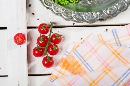 Tomato twig lays on board near white napkinの写真素材
