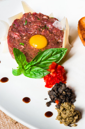 Classic tartare with fresh basil and parmesan slicesの写真素材