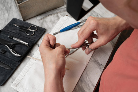 A woman makes herself a manicure, removes the cuticle skin on her nails, takes care of her nails....