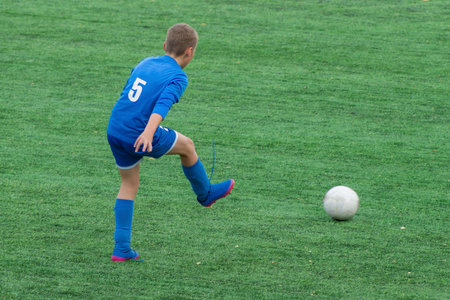 Children's football. An interesting football moment at the match and training. The active struggle and dynamics of the boys' soccer match. The boys are recklessly fighting for the ball.の写真素材