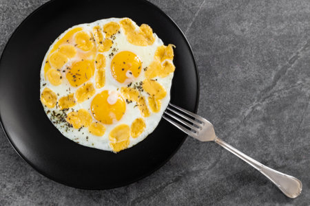 Fried eggs in a pan with butter for breakfast or lunch simple cooking, delicious food with bread and pita bread.の写真素材