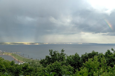 Thunderstorm and rainbow with sun rays over the Volga river.