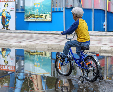 Ulyanovsk, Russia - September 07, 2013: The boy rides his bike through the puddles after the rain.の写真素材