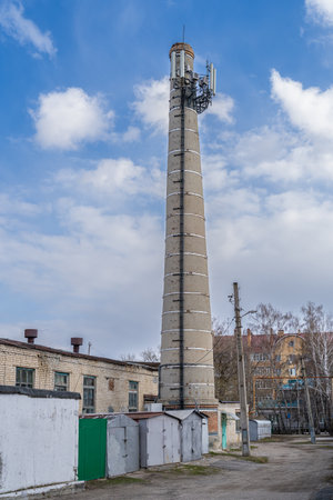 A large tall brick chimney venting smoke while burning coal to heat homes became the city tower for cell phone equipment.の写真素材