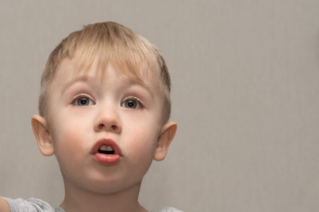 The face of a cute blond boy 3 years old close-up with facial expressions and emotions of an indignant child.の写真素材