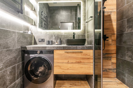 A modern bathroom with a washing machine. The interior is decorated in gray and wooden tones.の写真素材