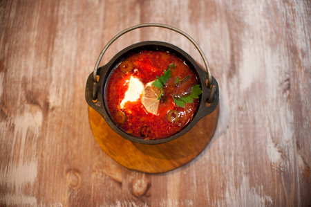 food photo top view in the center Solyanka-tomato soup with a slice of lemon and sour cream in a...