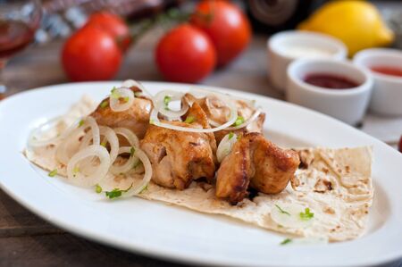 Meat kebab with onions on a white plate on a wooden background. Grilled meatの写真素材