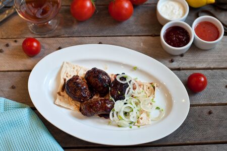 Meat kebab with onions on a white plate on a wooden background. Grilled meatの写真素材