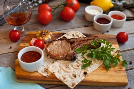 Steak on the bone. Steak on a wooden Board with vegetables and herbs. The view from the top.の写真素材