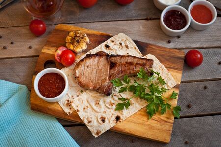 Steak on the bone. Steak on a wooden Board with vegetables and herbs. The view from the top.の写真素材