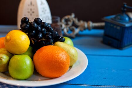 assorted fruit in a white plate on a blue wooden backgroundの写真素材