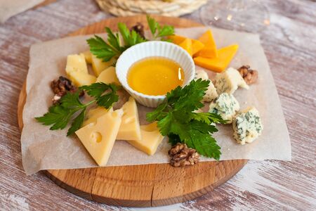 Still life cheese dish with nuts and honey on a wooden boardの写真素材