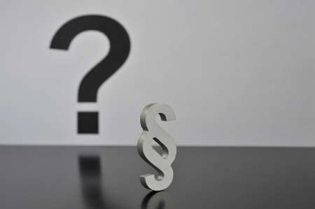 Hamburg, Germany - April 9, 2017: Close up of a metal paragraph sign in front of a question mark - symbolizes the uncertainty in courtの写真素材