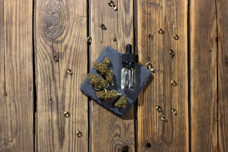 Medical cbd oil in a glass bottle with a pipette surrounded by dry marijuana buds and cbd extract in...