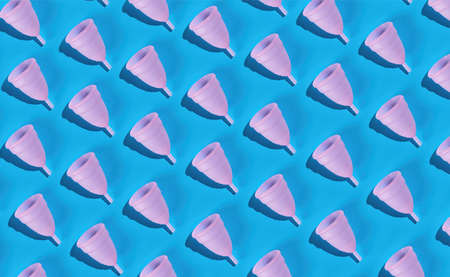Seamless pattern of a pink menstrual cup made of delicate medical silicone on a blue background. Large photo sizeの写真素材