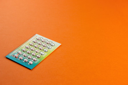 Female oral contraceptive pills blister on orange background. Female contraceptive hormonal birth control pills. The concept of pregnancy planning. copy spaceの写真素材