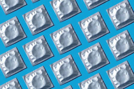 Seamless pattern of condoms in foil packaging on a blue background. Safe sex and reproductive health concept.の写真素材