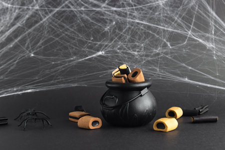 holiday sweets in a witch's cauldron and next to it on a black background with cobwebsの写真素材