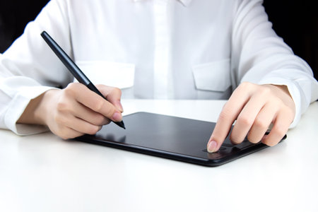 A young girl works on a wireless graphics tablet, holds a pen in one hand, and presses a button with the otherの写真素材
