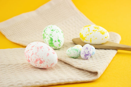 Composition of painted eggs, chicken and quail with a wooden spoon and a beige kitchen towel, on a...