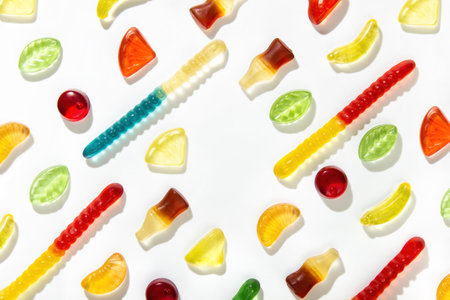 Chewing marmalade of different shapes, tastes and colors lie in a pattern on a white background. Free space in the centerの写真素材