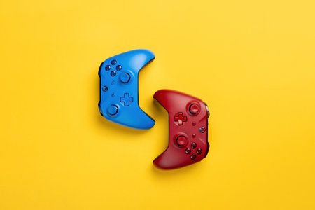 Two xbox brand wireless gamepads red and blue lie on a yellow background back to back. Team play, lots of spaceのeditorial素材