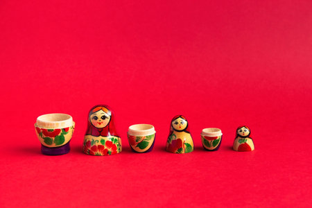 A set of wooden matryoshka dolls stand on a red background in order of size