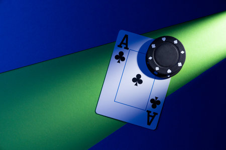 A plastic playing card lies on a blue-green background, next to a pair of chips.の写真素材