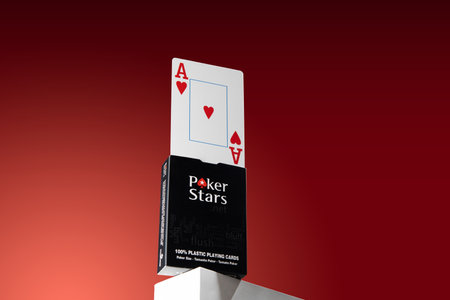 A plastic playing card stands on a box of poker stars cards. On a red backgroundのeditorial素材