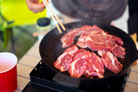 Lamb steaks being grilled on a hot pan with chopsticksの写真素材