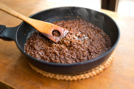 Frying pan with a mixture of ground and ground coffee on a wooden tableの写真素材