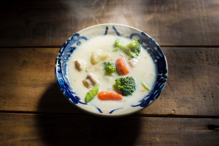 thai style noodle soup with chicken and vegetables on wooden table