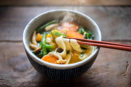 Japanese noodle soup with vegetables and chopsticks on wooden table.の写真素材