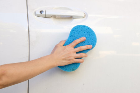 close up of hand washing a car with sponge and soap