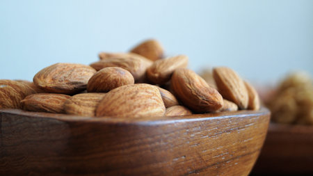 Almond nuts in a wooden bowl on a blue background. close up.の写真素材