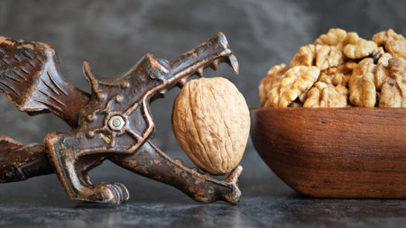 Walnuts in a wooden bowl and nutcracker on a dark backgroundの写真素材
